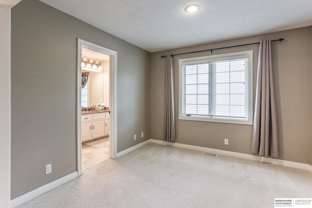 unfurnished room with baseboards, visible vents, and light carpet