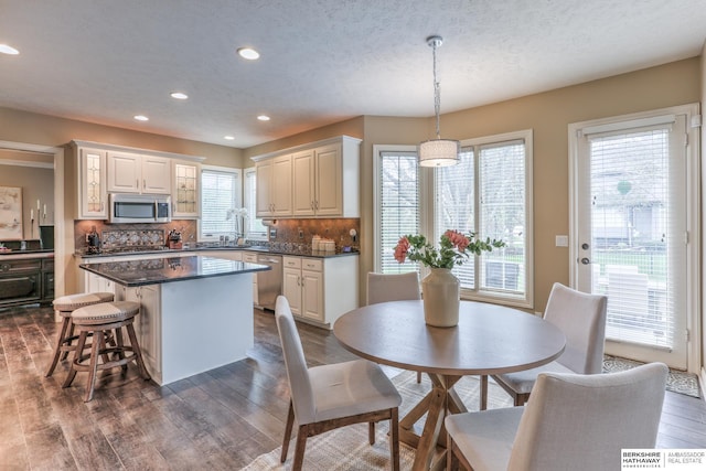 kitchen with dark countertops, a center island, stainless steel appliances, recessed lighting, and dark wood-type flooring