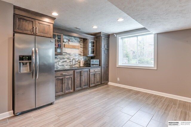 kitchen featuring baseboards, a textured ceiling, tasteful backsplash, and stainless steel fridge with ice dispenser