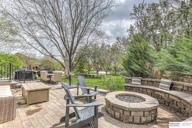 view of patio / terrace with a fire pit, a deck, and outdoor dining space