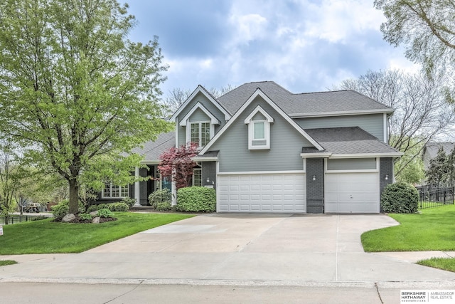 craftsman inspired home with roof with shingles, a front yard, a garage, fence, and concrete driveway