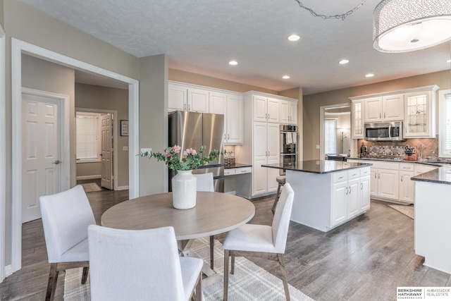 kitchen featuring white cabinets, dark countertops, appliances with stainless steel finishes, wood finished floors, and a kitchen island