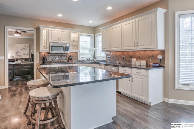 kitchen featuring stainless steel appliances, a breakfast bar, dark wood-style floors, and white cabinetry