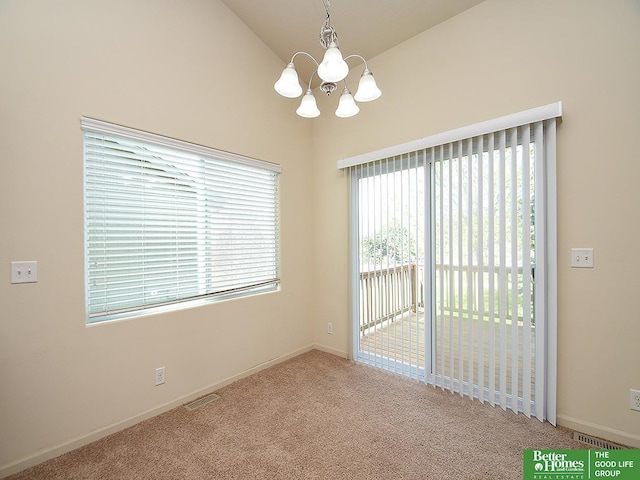 carpeted spare room featuring baseboards, a chandelier, vaulted ceiling, and visible vents