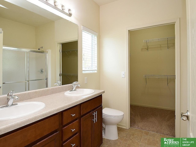 bathroom featuring a sink, a stall shower, toilet, and double vanity