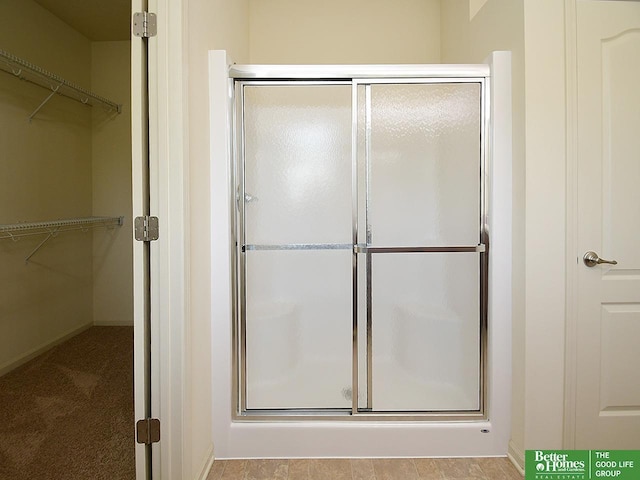 full bath with baseboards, a walk in closet, and a shower stall