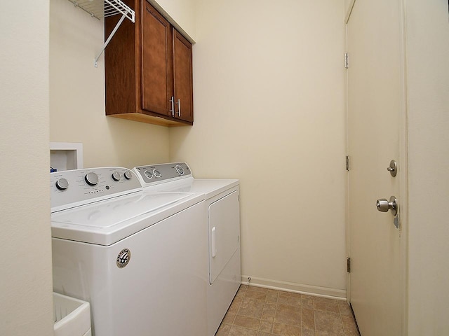 washroom with baseboards, cabinet space, and independent washer and dryer