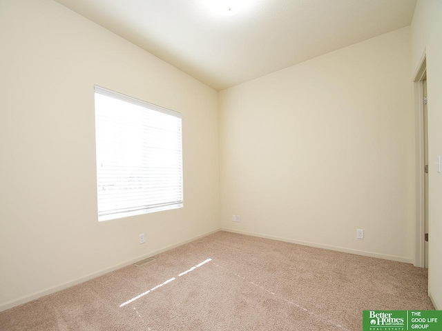 carpeted spare room with baseboards, lofted ceiling, and visible vents