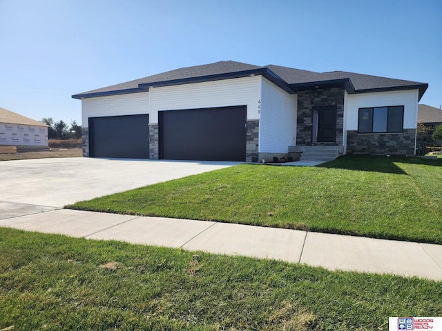 prairie-style house with concrete driveway, a front yard, stone siding, and a garage