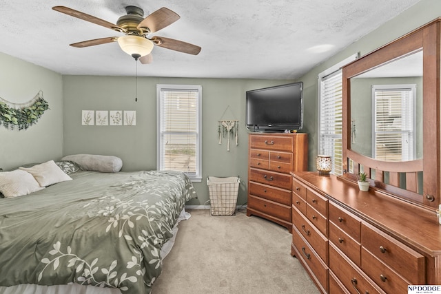 bedroom featuring baseboards, a ceiling fan, a textured ceiling, and light carpet