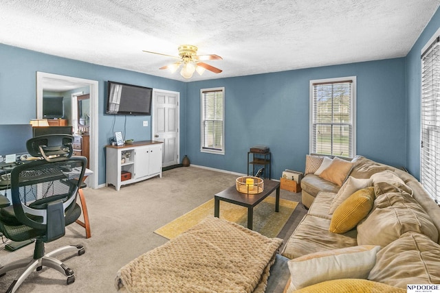 carpeted living area featuring baseboards, a ceiling fan, and a textured ceiling