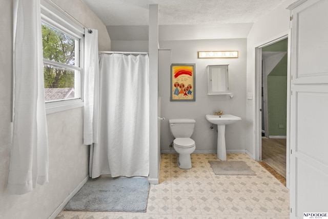 bathroom featuring a textured ceiling, baseboards, tile patterned floors, toilet, and a shower with shower curtain