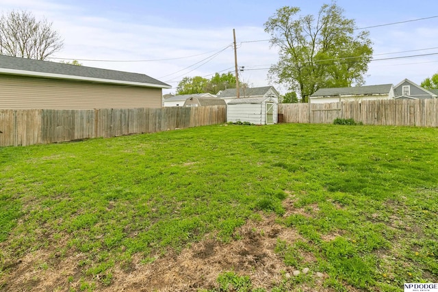 view of yard with an outbuilding, a fenced backyard, and a shed