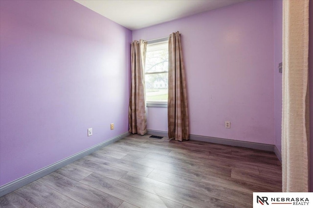 unfurnished room with baseboards and wood finished floors