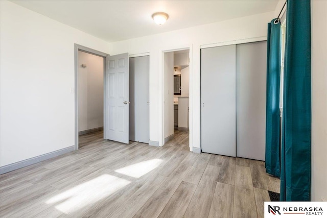 unfurnished bedroom with light wood-type flooring, baseboards, and a closet