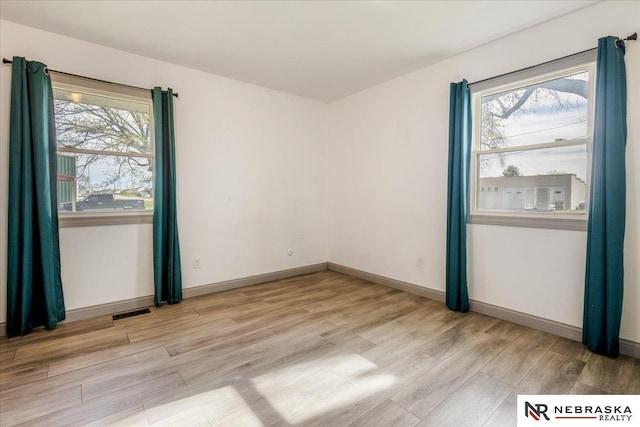 unfurnished room with light wood-type flooring, baseboards, plenty of natural light, and visible vents