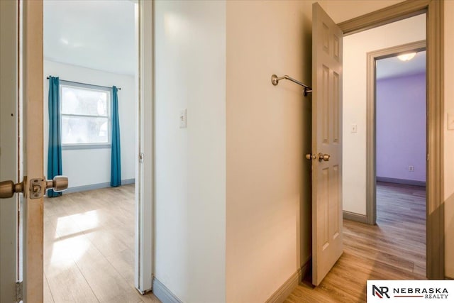 hall with baseboards and light wood-style flooring