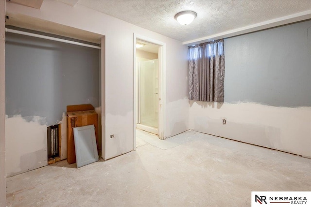 unfurnished bedroom with ensuite bathroom, a textured ceiling, and concrete floors