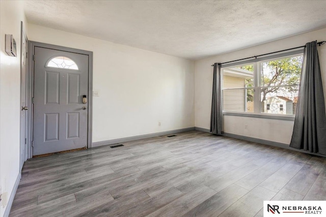 foyer featuring visible vents, light wood finished floors, baseboards, and a healthy amount of sunlight