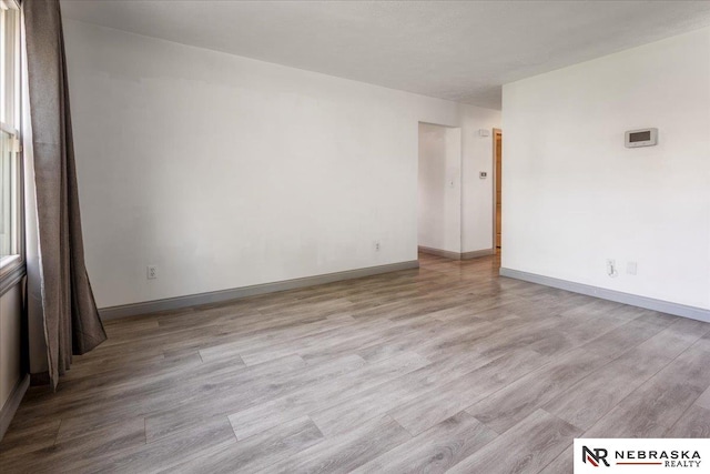 empty room with baseboards and light wood finished floors