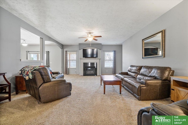 7714 S 167th St, Omaha, NE 68136 - carpeted living room with arched walkways, a textured ceiling, ceiling fan, and a glass covered fireplace