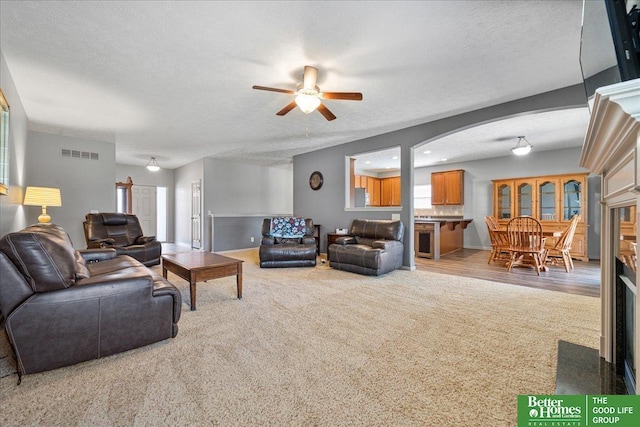 7714 S 167th St, Omaha, NE 68136 - carpeted living room with visible vents, baseboards, ceiling fan, a textured ceiling, and arched walkways