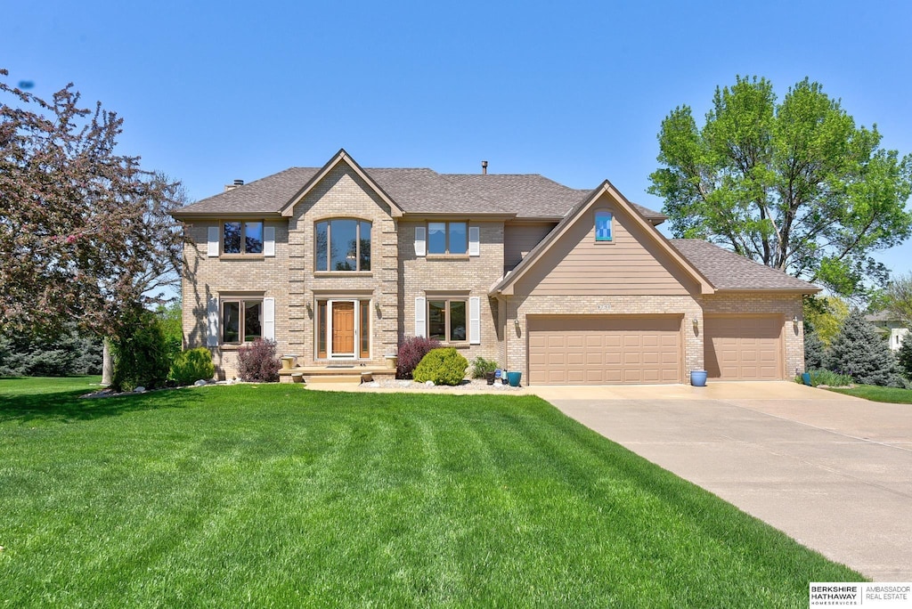 view of front facade with brick siding, an attached garage, driveway, and a front lawn