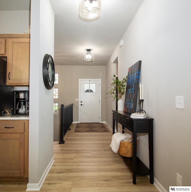 doorway to outside featuring baseboards and light wood finished floors