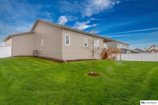 rear view of house featuring stairway, a lawn, fence, and central AC unit