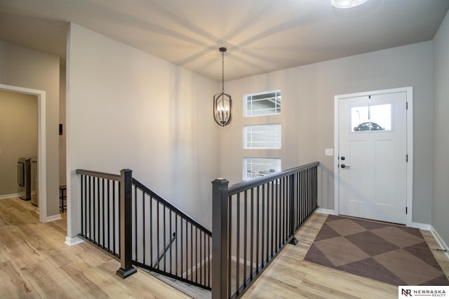 entryway featuring baseboards, a notable chandelier, and light wood-type flooring