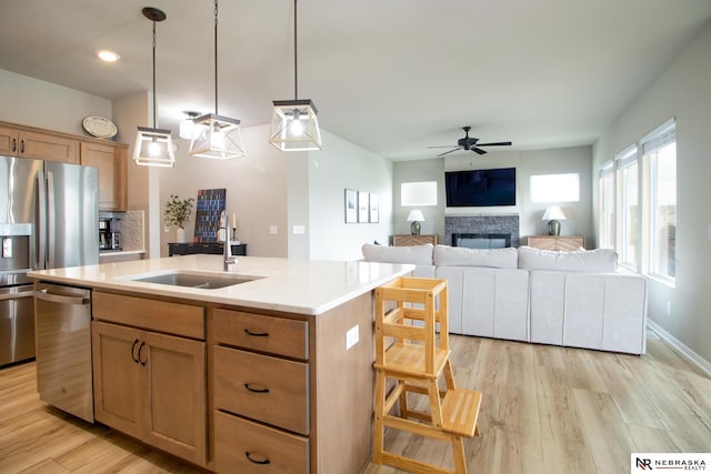 kitchen with an island with sink, ceiling fan, light countertops, a sink, and appliances with stainless steel finishes
