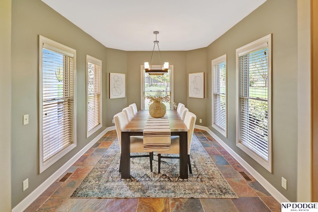 dining room featuring baseboards, stone tile floors, and a wealth of natural light