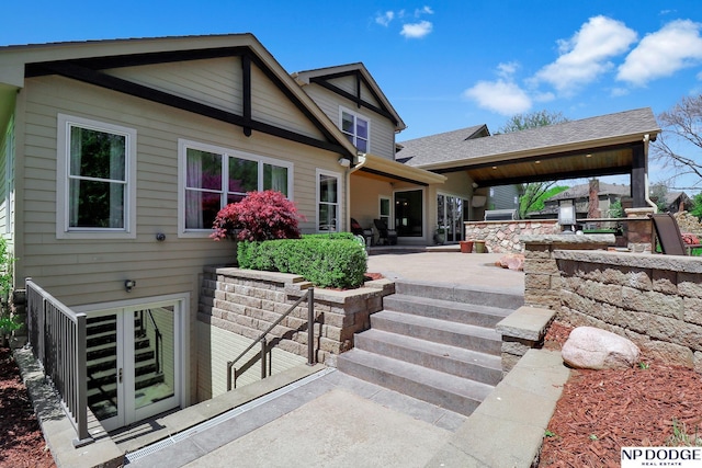 rear view of house with a shingled roof and a patio area