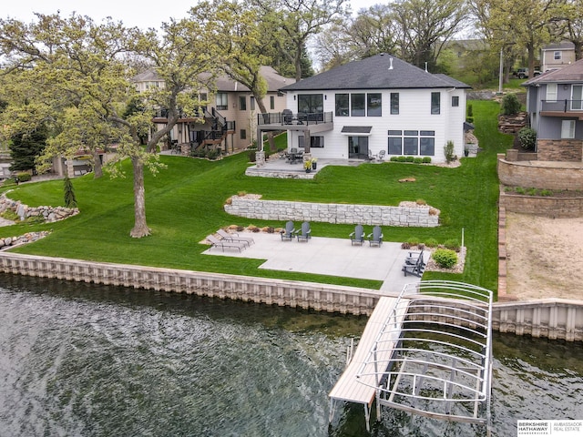 rear view of house featuring a lawn, a patio, and a water view