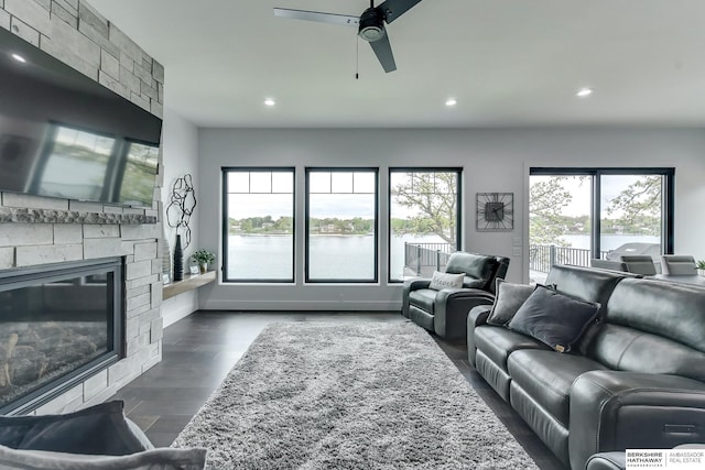 living room featuring a water view, a fireplace, a ceiling fan, and recessed lighting