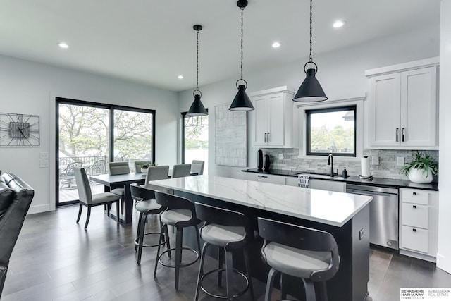 kitchen with a center island, tasteful backsplash, stainless steel dishwasher, a sink, and recessed lighting