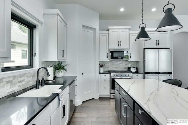 kitchen featuring appliances with stainless steel finishes, white cabinets, backsplash, and decorative light fixtures