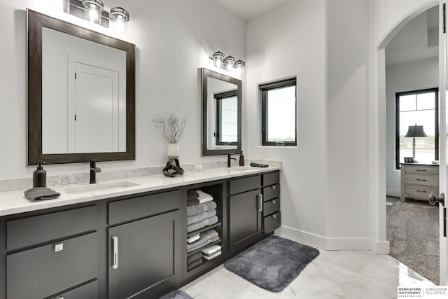 bathroom featuring a sink, baseboards, double vanity, and marble finish floor