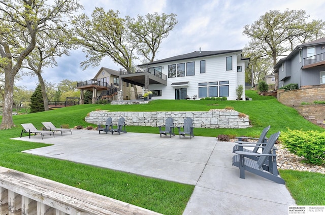 back of property with a lawn, a patio, and a balcony