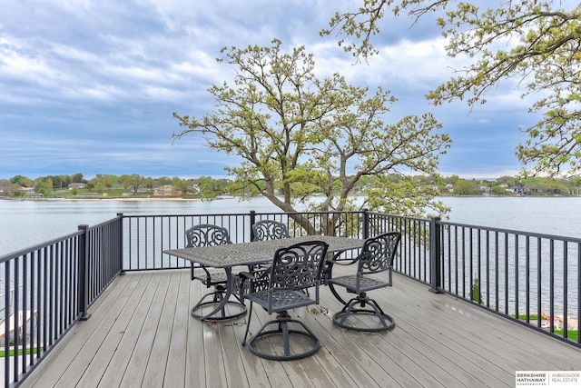 wooden terrace with a water view and outdoor dining space
