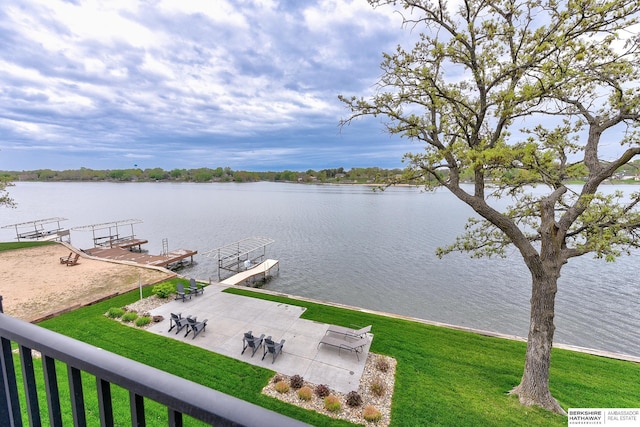 view of dock featuring a patio, a water view, and a yard