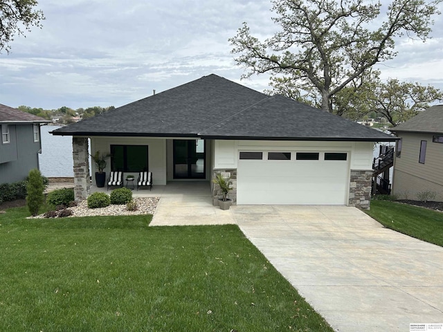 view of front of property with driveway, a front yard, a garage, a shingled roof, and stone siding