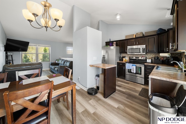 kitchen featuring a sink, appliances with stainless steel finishes, vaulted ceiling, and light countertops