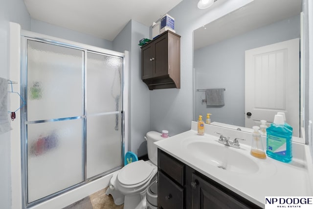 bathroom with vanity, a shower stall, and toilet