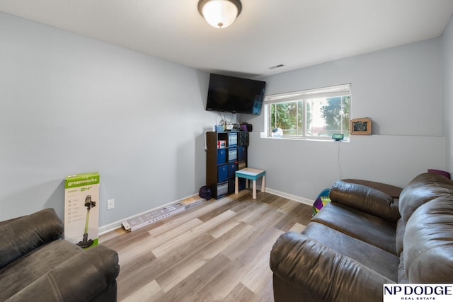 living area featuring baseboards, light wood-style flooring, and visible vents