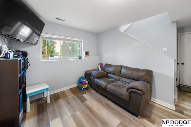 living area with baseboards, light wood-type flooring, and visible vents