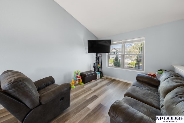 living area with baseboards, vaulted ceiling, and wood finished floors