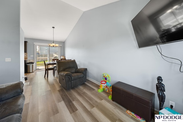 living room with an inviting chandelier, wood finished floors, and vaulted ceiling