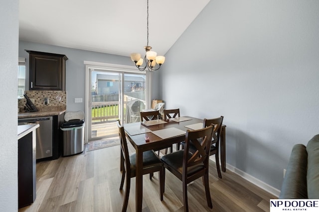 dining area with baseboards, light wood-style flooring, lofted ceiling, and a notable chandelier