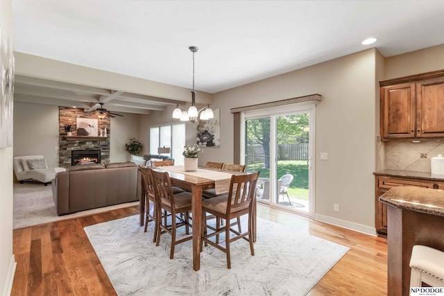 dining area featuring a stone fireplace, recessed lighting, beam ceiling, and light wood-type flooring